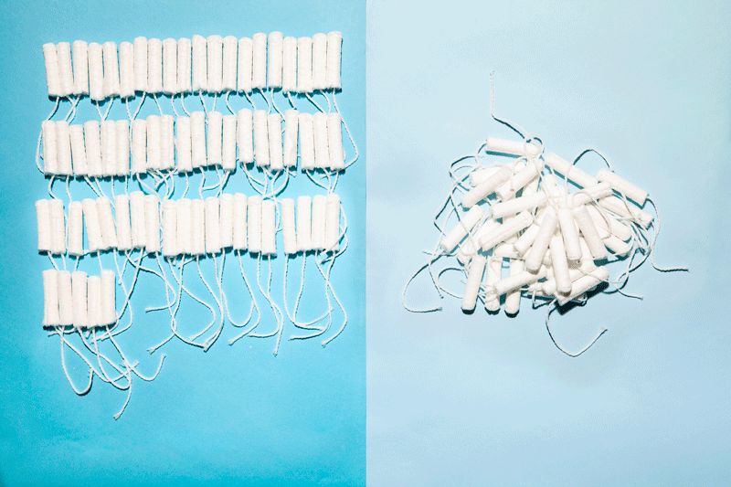 Pile of over-the-counter health projects on left and single tampon on right in front of teal background